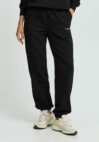Sorte sweatpants lavet af blødt stof, med elastisk talje og snøre, sidelommer og tapered manchetter. Brandlogo på øvre lår.
