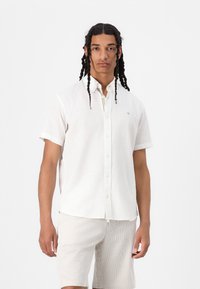 Korte mouwen witte linnen shirt met een button-down kraag, voorzien van een klein logo. Gecombineerd met beige gestreepte shorts. Geweven materiaal.