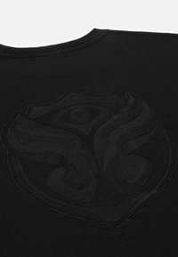 Zwarte t-shirt met een tonale, textuur logo in de vorm van een schild met golvende ontwerpen. Gemaakt van zachte stof met een geribde halslijn.