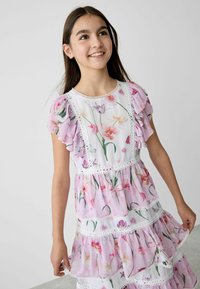 Blumendruckkleid in einem hellvioletten Farbton, mit geschichteten Rüschen und weißen Spitzenakzenten entlang des Ausschnitts und der Stufen.