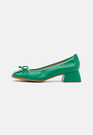 Chaussure femme à talon bas en cuir vert, avec un bout carré, un petit nœud sur le devant et un talon bloc sur fond blanc.