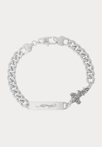 Stříbrný náramek s řetízkem, který obsahuje plochou štítkovou destičku s vyrytým nápisem, dekorativní kříž a designové detaily růže. Součástí je zapínání.