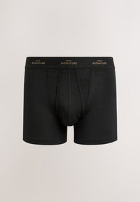 Boxers noirs avec une ceinture élastique comportant le logo doré "Next Signature", présentés sur un fond neutre uni.