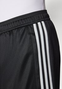 Schwarze Sportshorts mit elastischem Bund, ausgestattet mit drei weißen vertikalen Streifen an der Seite für zusätzlichen Detail. Leichtes Material.