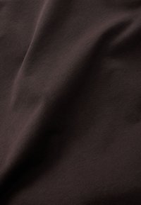 Tissu brun foncé avec une texture lisse, légèrement extensible, présentant un éclat subtil et une surface à maille serrée.