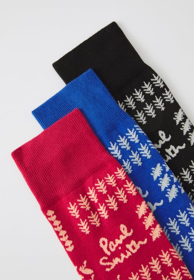 Tres pares de calcetines de punto en rojo, azul y negro. Cada par presenta un patrón contrastante y texto, con puños acanalados y una textura suave.
