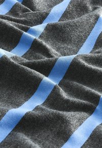 Blødt gråt stof med en glat tekstur, der har vandrette lysblå striber. Materialet ser ud til at være strikket med synlige fibre og blød drapering.