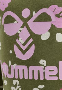 Grönt tyg med en stor rosa varumärkeslogotyp och abstrakta vita former. Designen har ett strukturerat, avslappnat utseende.