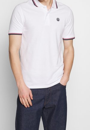 Camisa polo blanca con un cierre de dos botones, con un ribete en rojo y azul marino contrastante en el cuello y las mangas, y un pequeño logotipo bordado en el pecho.