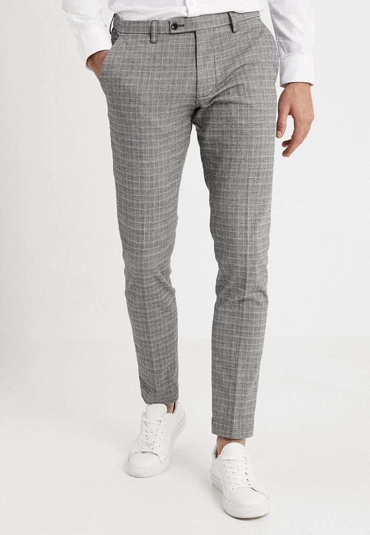 Šedé kostkované kalhoty slim fit s předními kapsami, poutky na opasek a plochým předním dílem, zakončené bílými teniskami.