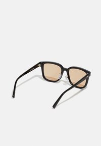 Ochelari de soare pătrați negri cu lentile brune; ramă din plastic lucios; accente metalice lângă balamale; brațe drepte; pernuțe pentru nas ajustabile.
