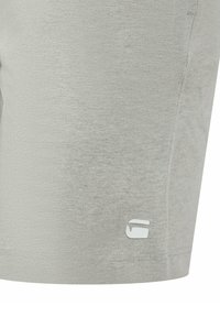 Graue Baumwoll-Shorts mit einer schlichten Textur, ausgestattet mit einem kleinen weißen Logo am Unterschenkel. Das Design umfasst genähte Säume und eine bequeme Passform.