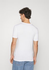 T-shirt bianco a maniche corte realizzato in tessuto morbido, con collo rotondo e vestibilità aderente, dalla superficie liscia e senza motivi visibili.