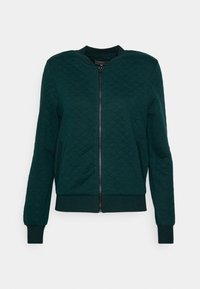 Prošívaná bomber bunda ve tmavě zelené barvě, s předním zipovým uzávěrem, žebrovanými manžetami a lemem. Hladká textura s designem v diamantovém vzoru.