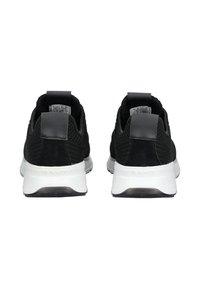 Paire de baskets noires avec semelles blanches vues de dos, avec tissu en maille et languettes au talon.