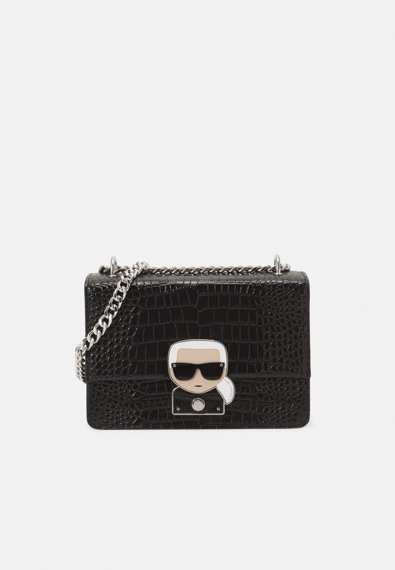 Sac à main en cuir synthétique noir effet crocodile avec bandoulière chaîne, doté d'un détail frontal de personnage style pop art et d'une fermeture à bouton-pression.