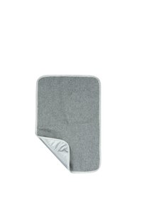 Tapete rectangular gris de tela con esquinas redondeadas y una esquina parcialmente doblada que revela un respaldo plateado liso.