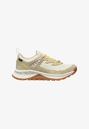 Scarpa sportiva beige realizzata in materiali mesh e suede, con dettagli gialli, suola testurizzata e intersuola ammortizzata. Presenta un pratico tirante.