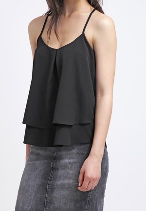 Black layered tank top with thin straps, featuring a flowing design and soft texture. Paired with a gray denim skirt.