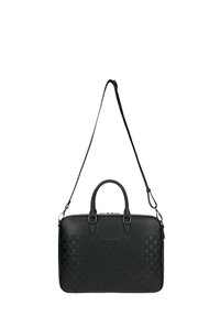 Schwarze Leder-Aktentasche mit gesteppter Musterung, zwei oberen Griffen und verstellbarem Schulterriemen, die vor einem weißen Hintergrund hängt.