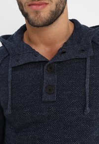 Felpa con cappuccio a maglia blu navy con un motivo testurizzato, dotata di un cappuccio con cordino, due bottoni neri e una vestibilità aderente.