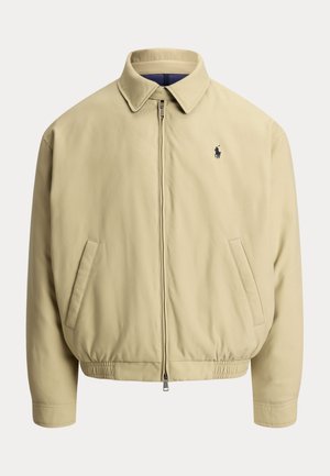 Veste beige zippée avec col, deux poches latérales, taille élastique et petit logo foncé sur la poitrine gauche.