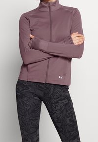 Light purple zip-up jacket with high collar, long sleeves, and thumbholes. Paired with black leggings featuring a textured abstract pattern.