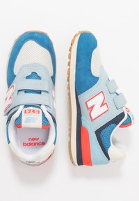 Baskets bleu et gris clair, en matériaux mesh et daim, avec des bandes Velcro, des accents rouges et une semelle en caoutchouc à motifs.