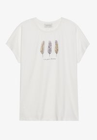 Balta medvilnės T-shirt marškiniai su laisvu siluetu, su trimis iliustruotomis plunksnomis purpurine ir geltona spalvomis, ir tekstu "gyvenk savo svajones" žemiau.