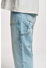 Light blue denim jeans featuring a relaxed fit, side pockets, and visible stitching details. The fabric has a soft, slightly worn texture.