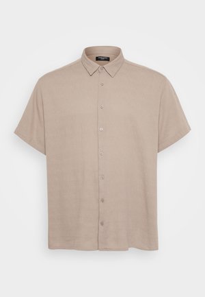 Camisa de manga corta con botones en tejido beis claro, con cuello y botones frontales. La textura parece suave y ligeramente texturizada.