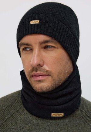 Black knit beanie and neck gaiter set made from soft material, featuring a ribbed design and a decorative label with "BELLEMERE NEW YORK."