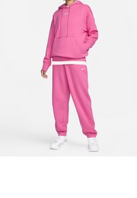 Pink hoodie and pants made of soft cotton blend, featuring a front pocket, drawstring hood, and Nike logo, paired with white sneakers.