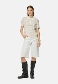 Svītrainā kokvilnas polo krekls ar baltu apkakli, apvienots ar baltām ceļgala garuma šortiem un melniem ādas ceļgala zābakiem.