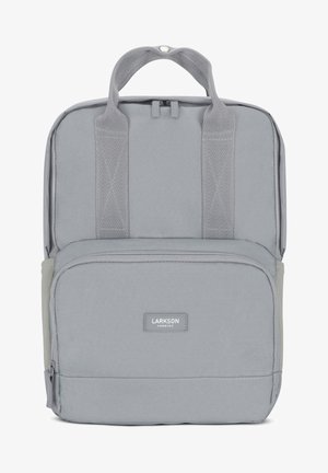 Grauer Stoff-Rucksack mit doppelten Schultergurten, vorderer Reißverschlusstasche und einem Tragegriff. Besitzt eine strukturierte Oberfläche und ein Markenlabel.