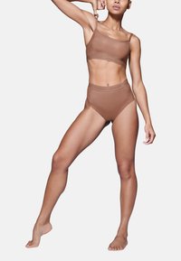 Set di reggiseno seamless marrone e mutande a vita alta. Materiale morbido, design minimalista, con una banda elastica caratterizzata da un logo discreto.