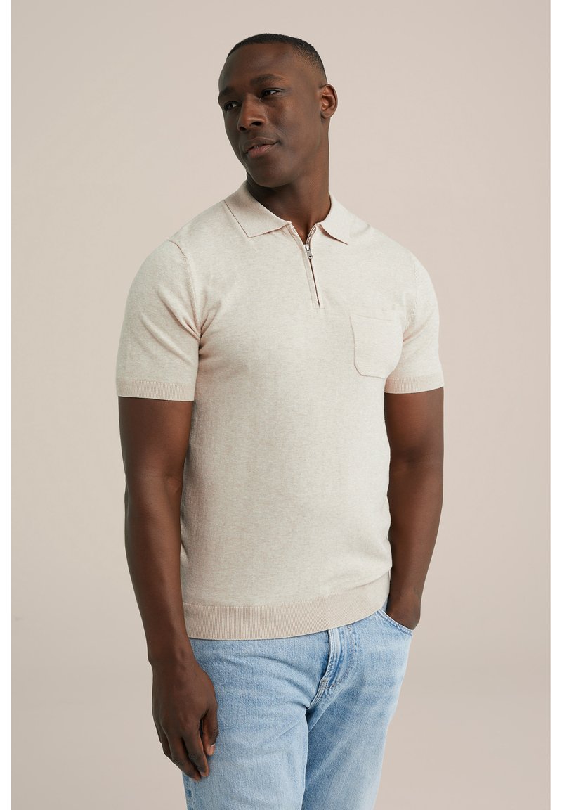 Beige short-sleeve polo shirt with a zipper collar, featuring a chest pocket and ribbed hem, paired with light blue jeans.