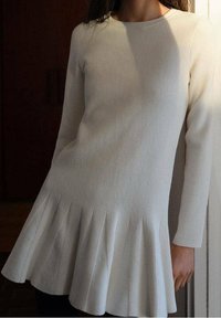 Robe en maille blanche douce avec manches longues, nervures texturées, ourlet évasé et encolure ronde. Matière lisse avec un corsage ajusté.