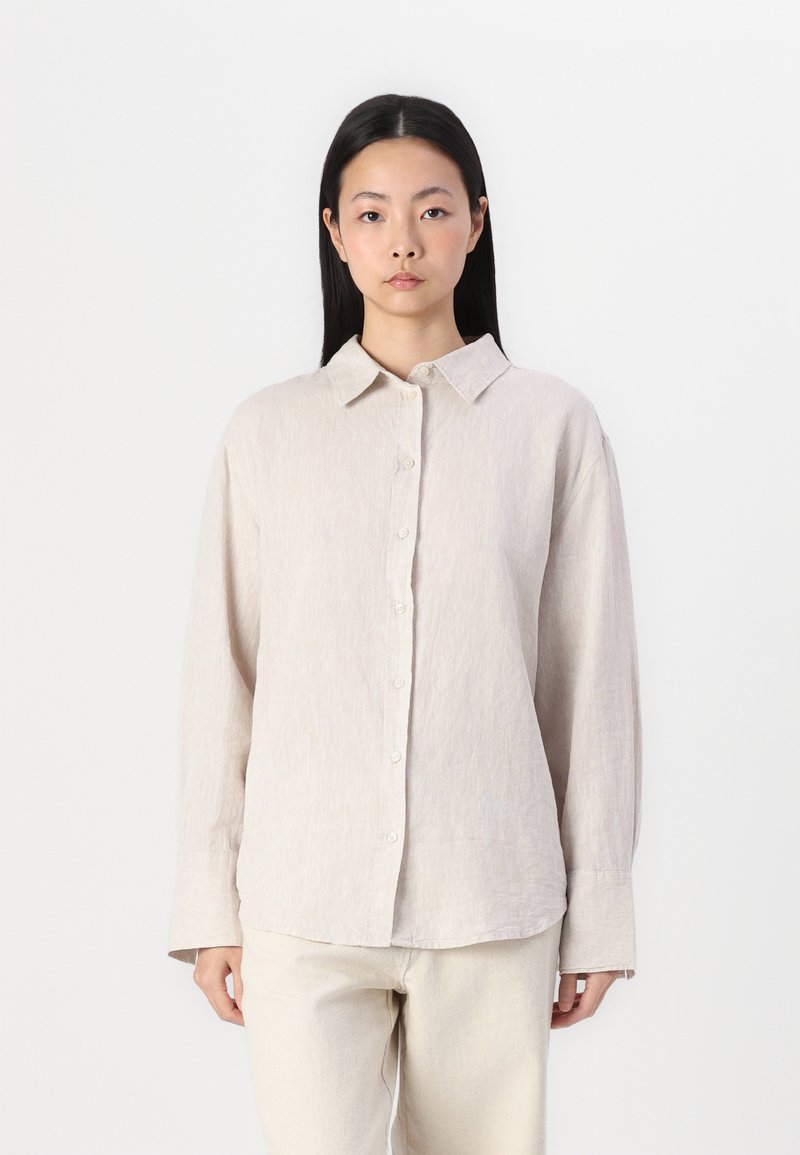 Gai bēšs lina krekls ar apkakles dekoltē, garām piedurknēm un pogājamu priekšpusi. Strukturēta auduma, ar brīvu piegriezumu.