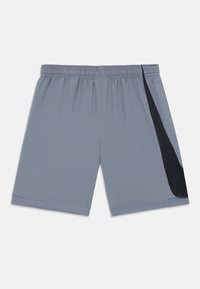 Shorts de sport gris avec une taille élastique, présentant un accent en maille noire d'un côté et un ourlet texturé. Tissu léger.