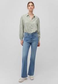 Light green patterned button-up shirt, blue flared jeans, and white sneakers. Cotton material, relaxed fit, with elastic sleeves and high waist design.