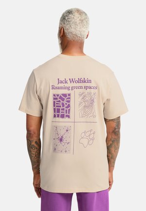 Beiges Baumwoll-T-Shirt mit lila Grafik auf der Rückseite, einschließlich Text und vier verschiedenen Mustern: Gitter, topografische Linien und ein Pfotenabdruck.