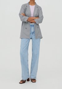 Grey checkered blazer with two buttons, light purple top, high-waisted light blue wide-leg jeans, and brown heeled sandals.