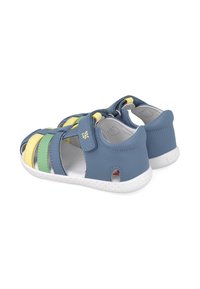 Sandalias de cuero azul con acentos en amarillo, verde y azul claro. Diseño abierto con una correa trasera y suela de goma texturizada blanca.