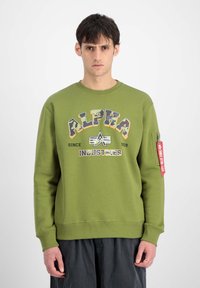 Felpa verde oliva con stampa del logo, collo a giro in costina e tasca con zip sulla manica con dettaglio tag rosso.