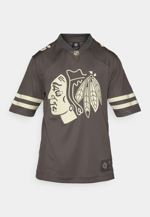 Maillot de hockey marron présentant un grand logo jaune d'un chef amérindien. Il possède des accents rayés sur les manches et un col rond.