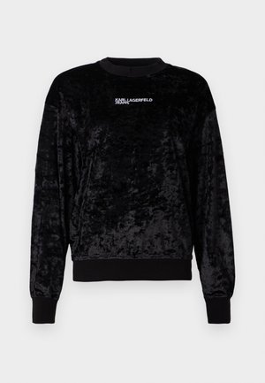 Black velvet sweatshirt with long sleeves, crew neck, ribbed cuffs, and hem. Features "KARL LAGERFELD JEANS" logo in white. Soft texture.