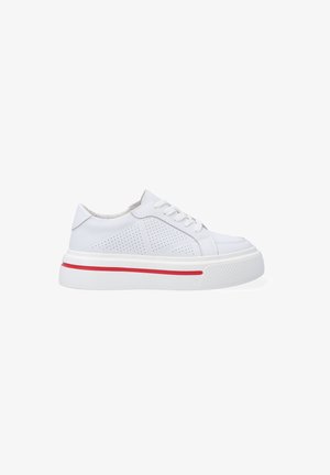 White sneaker shoe with perforated sides and red stripe on the sole. Features a rounded toe, flat laces, and a textured rubber outsole.