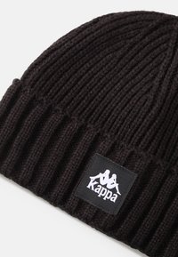 Gorro de lana negro, con textura de canalé, puño doblado y un parche rectangular con logotipo y marca en blanco.