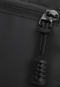 Pochette nera con zip realizzata in tessuto testurizzato, dotata di un robusto cordino intrecciato nero e di un tirazip in plastica stampata.